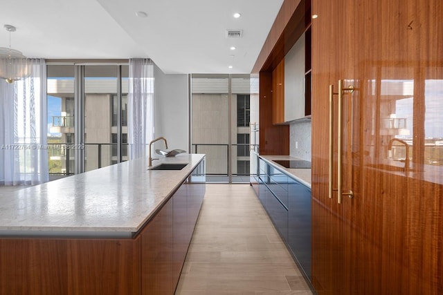 kitchen featuring sink, decorative backsplash, hanging light fixtures, a large island, and floor to ceiling windows