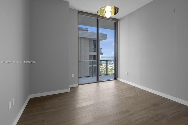 unfurnished room with dark wood-type flooring and a wall of windows