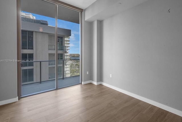 empty room with hardwood / wood-style flooring and a wall of windows