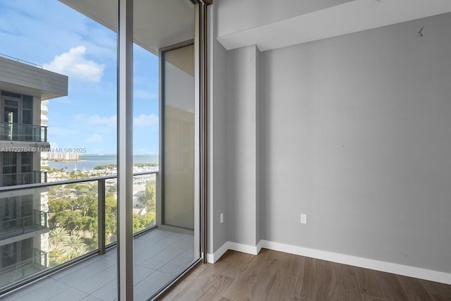 empty room featuring a water view, floor to ceiling windows, and hardwood / wood-style floors