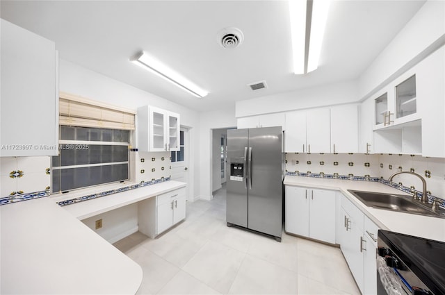 kitchen featuring white cabinetry, sink, decorative backsplash, light tile patterned floors, and appliances with stainless steel finishes