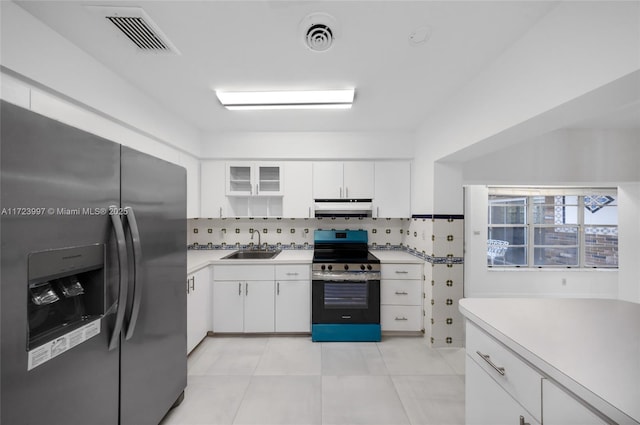 kitchen with tasteful backsplash, stainless steel appliances, sink, light tile patterned floors, and white cabinets