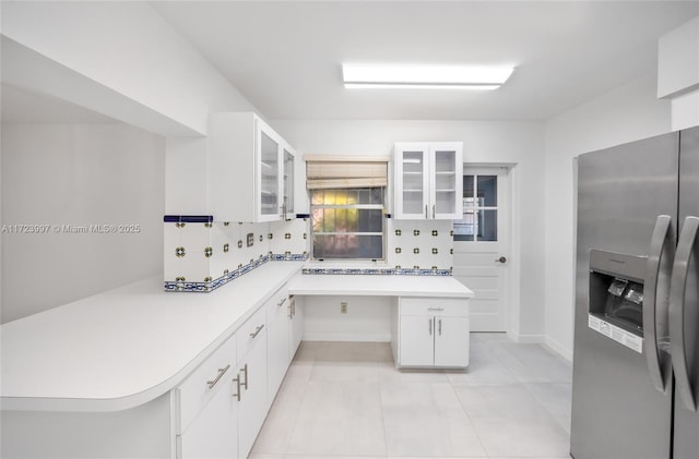 kitchen featuring backsplash, kitchen peninsula, white cabinetry, and stainless steel refrigerator with ice dispenser