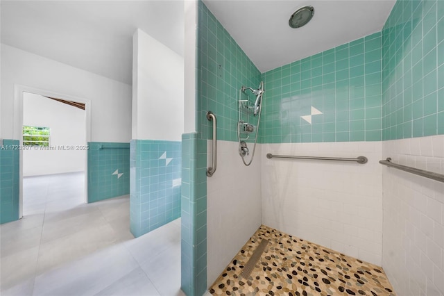 bathroom with tiled shower, tile patterned floors, and tile walls