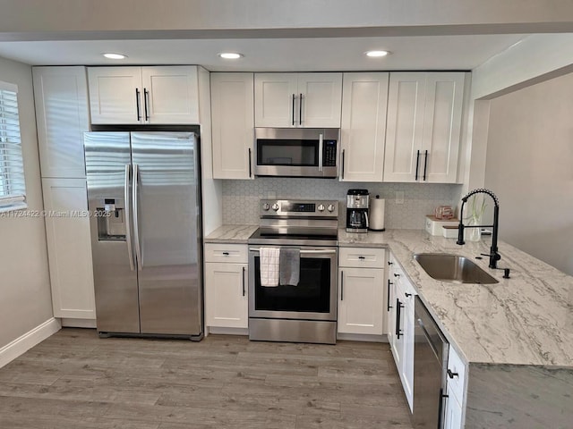 kitchen with light stone countertops, sink, white cabinetry, and stainless steel appliances