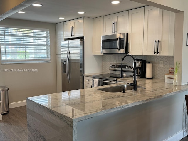 kitchen featuring white cabinetry, light stone countertops, kitchen peninsula, and stainless steel appliances