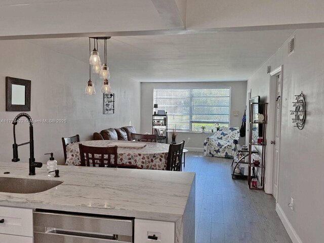 kitchen with dark hardwood / wood-style flooring, white cabinetry, hanging light fixtures, and sink