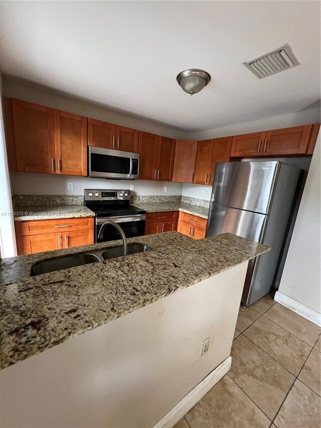 kitchen featuring kitchen peninsula, stainless steel appliances, light tile patterned flooring, and sink