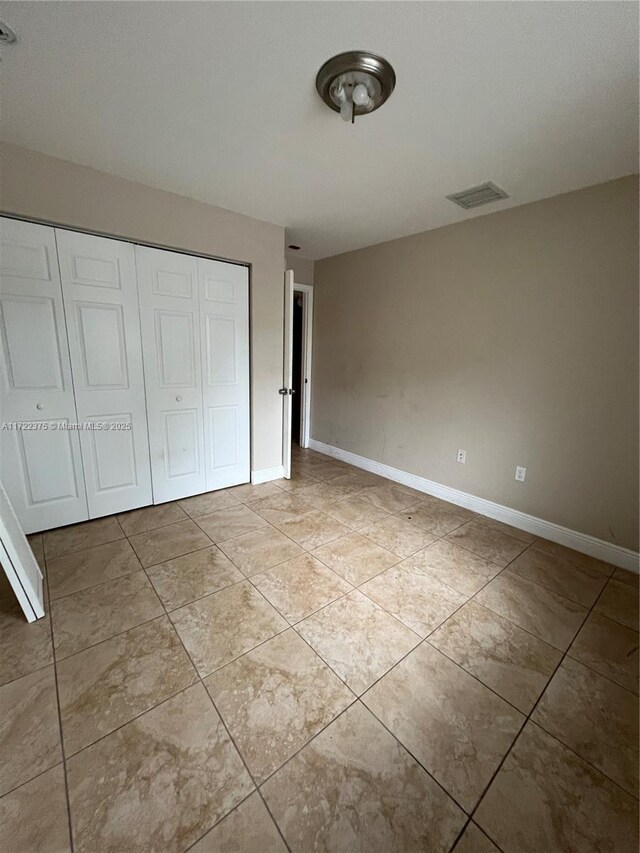 unfurnished bedroom featuring light tile patterned floors and a closet