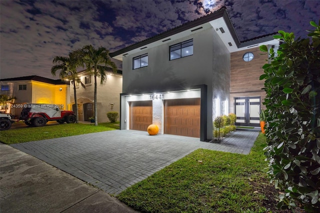 modern home featuring a lawn, french doors, and a garage