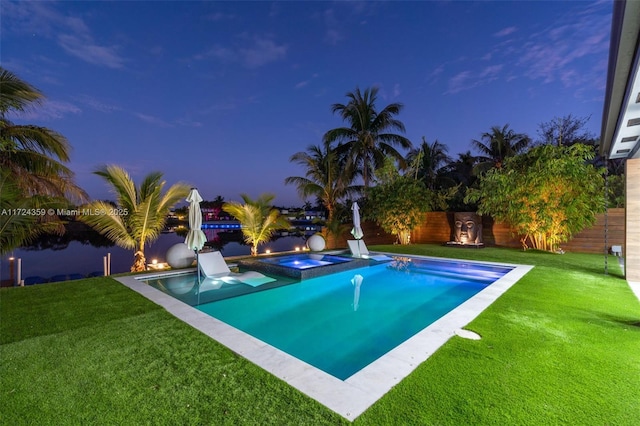 pool at dusk with an in ground hot tub and a lawn