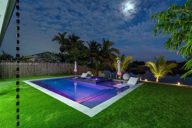 view of swimming pool featuring a lawn and an in ground hot tub