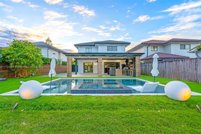 back of property with a patio, a lawn, and a pool with hot tub