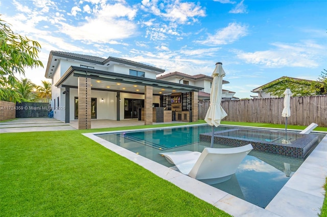 back of house featuring exterior bar, a yard, a fenced in pool, and a patio