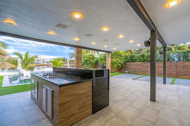 patio terrace at dusk featuring a water view and a bar