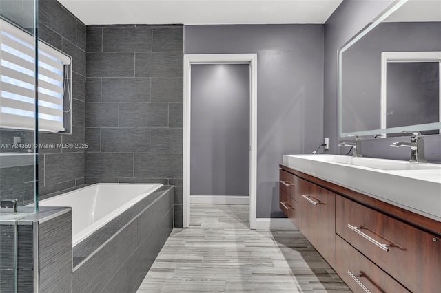 bathroom with tiled tub and vanity