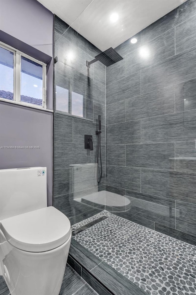 bathroom with tiled shower and toilet