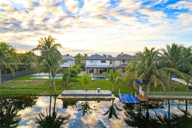 exterior space with a yard, a water view, and a fenced in pool