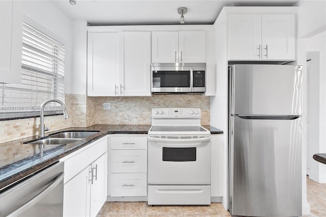 kitchen with sink, dark stone countertops, stainless steel appliances, white cabinets, and decorative backsplash