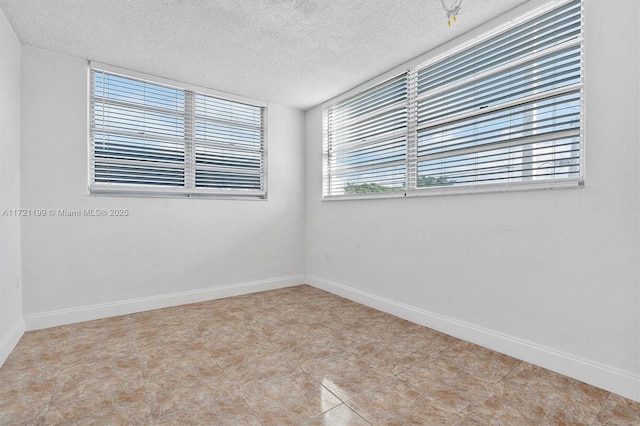 tiled empty room featuring a textured ceiling