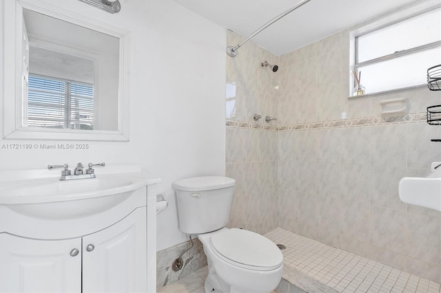 bathroom with vanity, a tile shower, and toilet