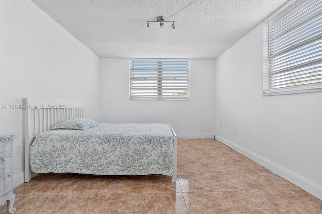 tiled bedroom with multiple windows and a textured ceiling