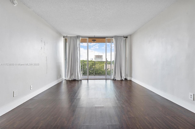 spare room with dark hardwood / wood-style flooring, a textured ceiling, and a wall of windows