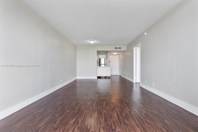 unfurnished living room featuring dark hardwood / wood-style flooring and a textured ceiling