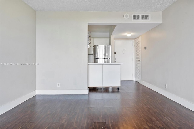 unfurnished room featuring dark hardwood / wood-style flooring and a textured ceiling