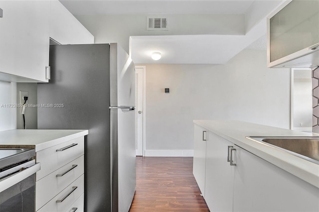 kitchen featuring white cabinets, dark hardwood / wood-style floors, sink, and stainless steel refrigerator