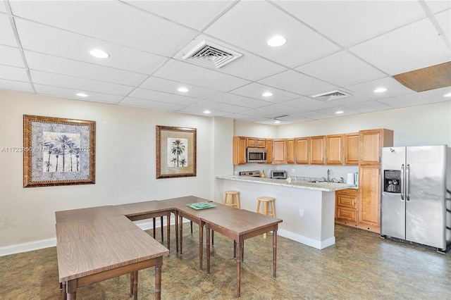 kitchen featuring light stone countertops, sink, stainless steel appliances, kitchen peninsula, and a breakfast bar