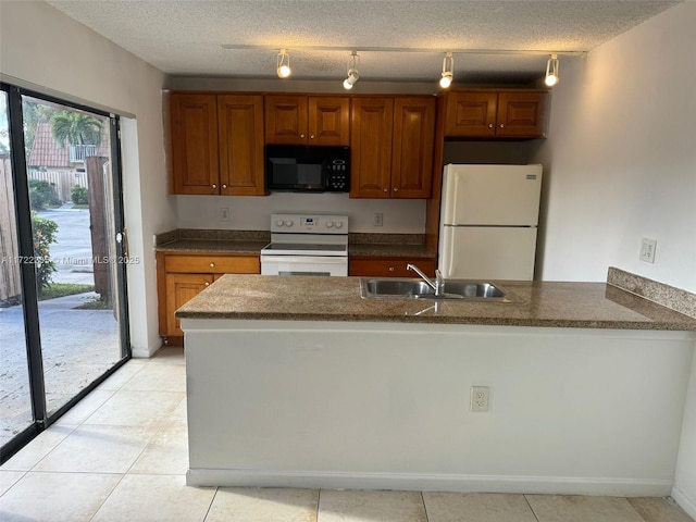 kitchen with a textured ceiling, white appliances, track lighting, and sink