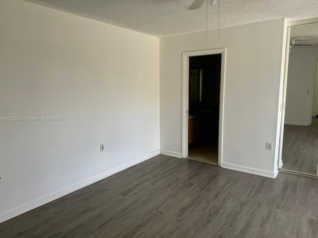 empty room with ceiling fan, dark hardwood / wood-style flooring, and a textured ceiling