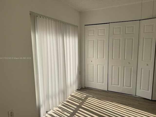 unfurnished bedroom featuring wood-type flooring, a textured ceiling, and a closet