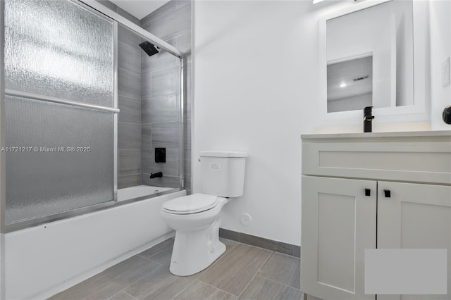 full bathroom featuring vanity, bath / shower combo with glass door, and toilet