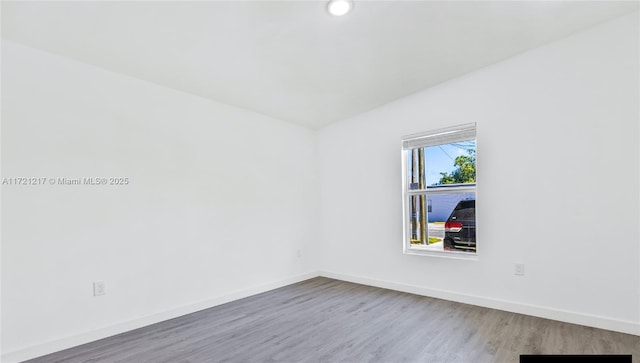 unfurnished room featuring wood-type flooring and vaulted ceiling