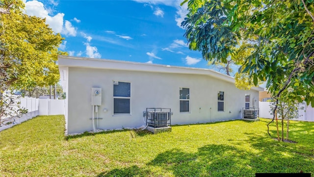 back of house with a lawn and central AC unit