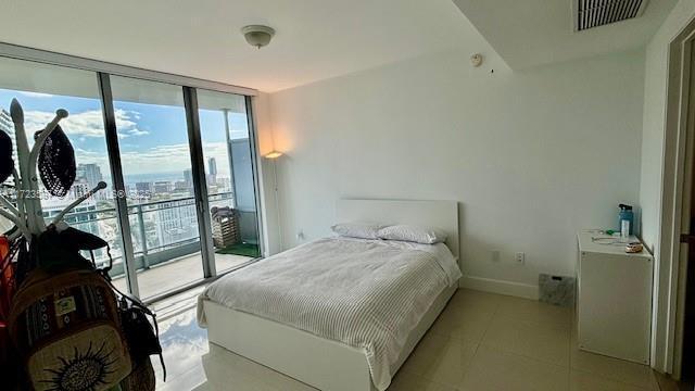 tiled bedroom featuring access to outside and floor to ceiling windows