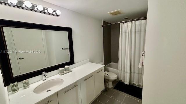 full bathroom featuring tile patterned floors, vanity, shower / bath combination with curtain, and toilet