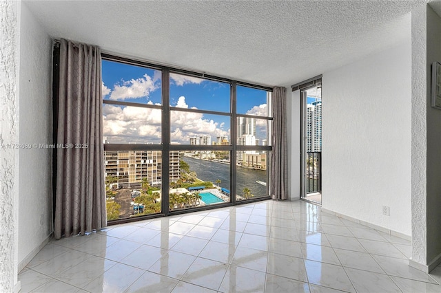 spare room featuring a wall of windows, light tile patterned floors, and a textured ceiling