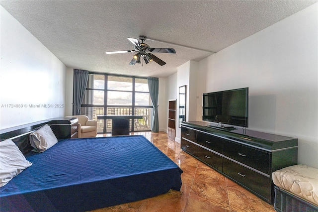 bedroom featuring ceiling fan, a textured ceiling, a wall of windows, and tile patterned flooring