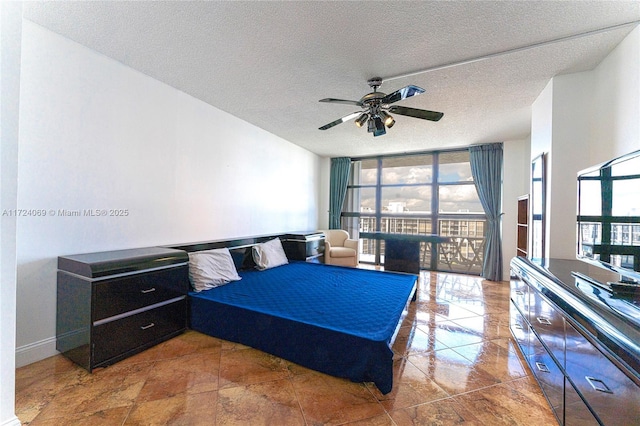 bedroom featuring ceiling fan, a textured ceiling, and expansive windows