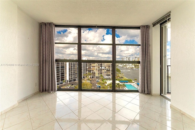 tiled empty room with a textured ceiling and floor to ceiling windows