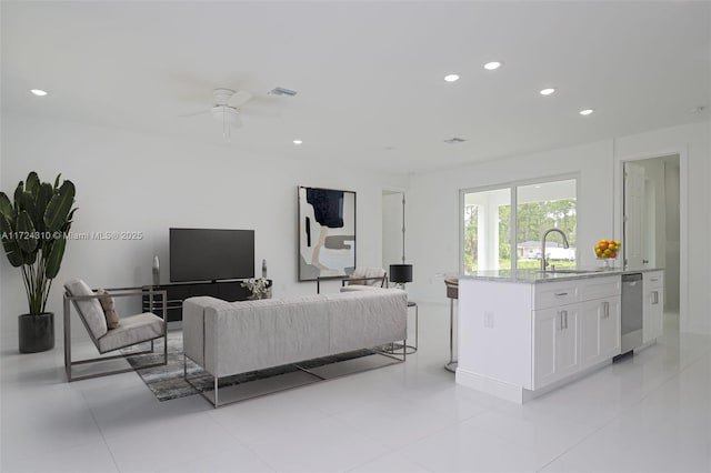 living room featuring light tile patterned flooring, ceiling fan, and sink