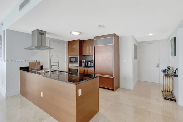 kitchen with sink, kitchen peninsula, built in appliances, dark stone counters, and exhaust hood