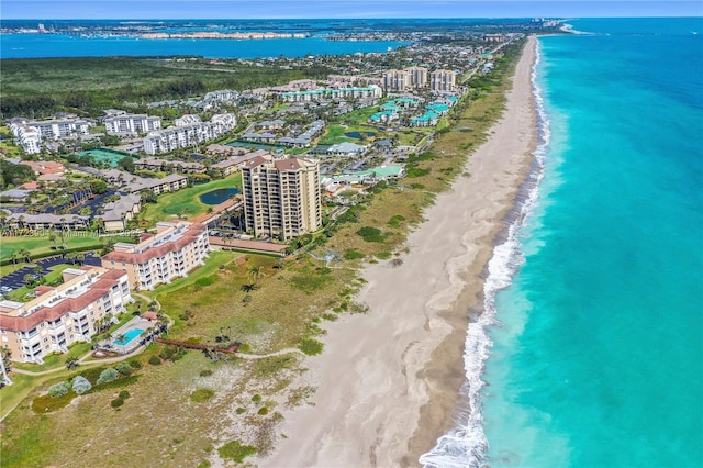 drone / aerial view featuring a water view, a view of city, and a beach view