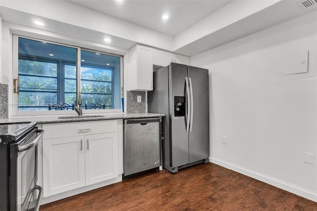 kitchen with dark wood-type flooring, white cabinets, decorative backsplash, light stone countertops, and stainless steel appliances