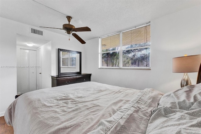 bedroom featuring wood-type flooring, a textured ceiling, a closet, and ceiling fan