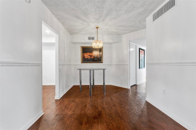 unfurnished dining area featuring dark wood-type flooring and a chandelier