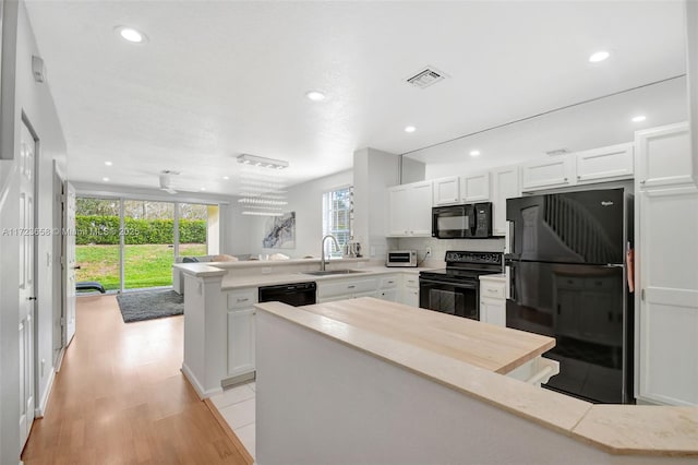 kitchen featuring black appliances, kitchen peninsula, sink, and white cabinetry